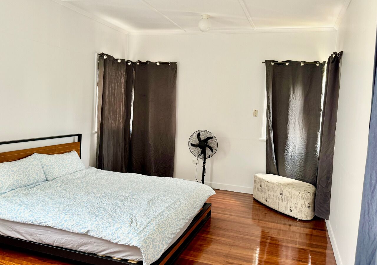 A bedroom with a bed, a bedside fan, and a bench.