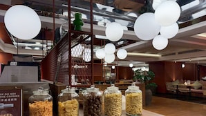 Una presentación de comida con diversas pastas y galletas en frascos de vidrio, utensilios de madera y un letrero que indica no tomar las galletas.
