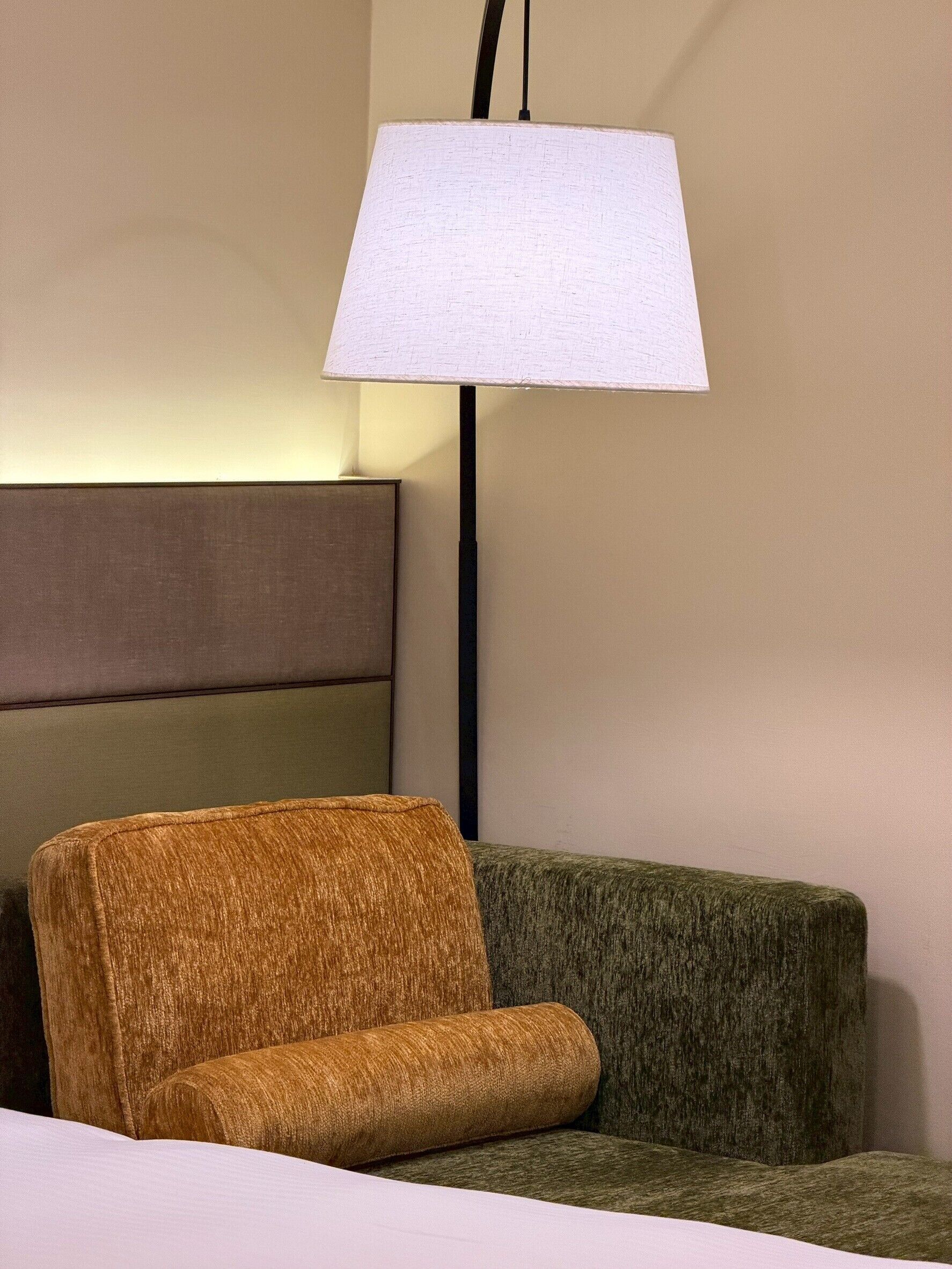 Quarto com sofá, luminária e parede.