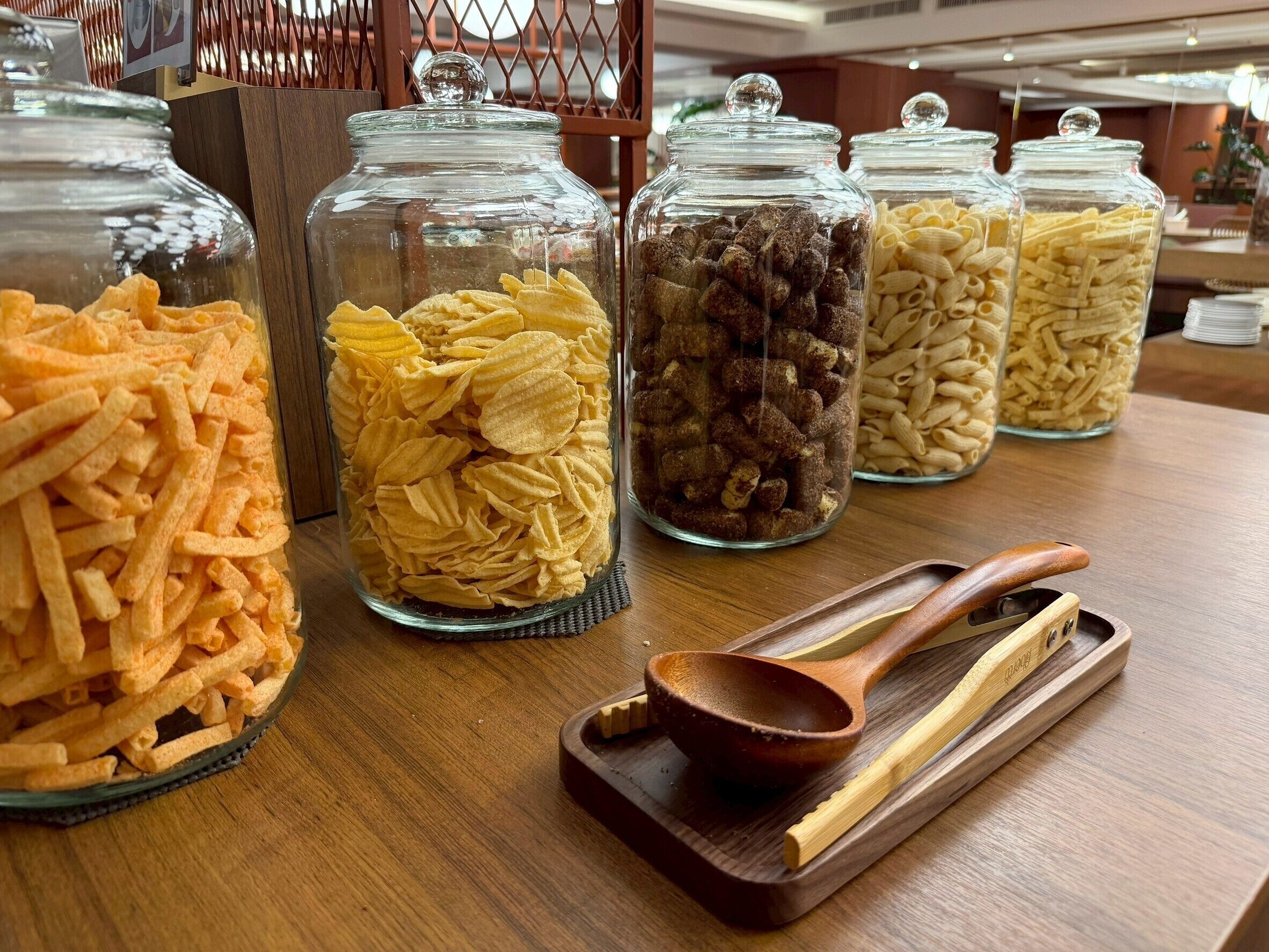 Glass jars filled with snacks on a wooden table.