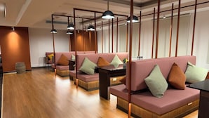 Un interior moderno con suelo de madera, asientos acolchados, iluminación colgante y un separador de madera.