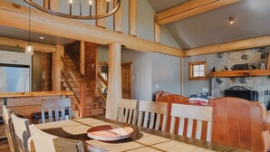 A spacious dining area with a wooden table and chairs, a chandelier, and a ceiling fan. - Beautiful Custom Log Home - 1 Mile to Sunday River, Walk to Matterhorn (Newry)