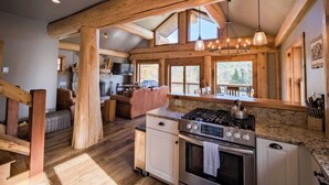 A spacious kitchen with wooden beams, a gas stove, and a large island. - Beautiful Custom Log Home - 1 Mile to Sunday River, Walk to Matterhorn (Newry)