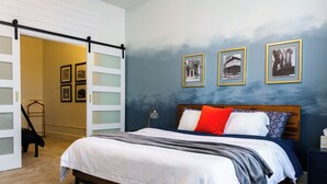 Ein Schlafzimmer mit einem Bett, einem Schrank mit Milchglasschränken und drei gerahmten Bildern an der Wand.