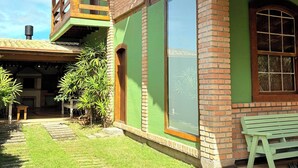 Uma casa de dois andares com varanda de madeira, fachada verde e chaminé de tijolos.