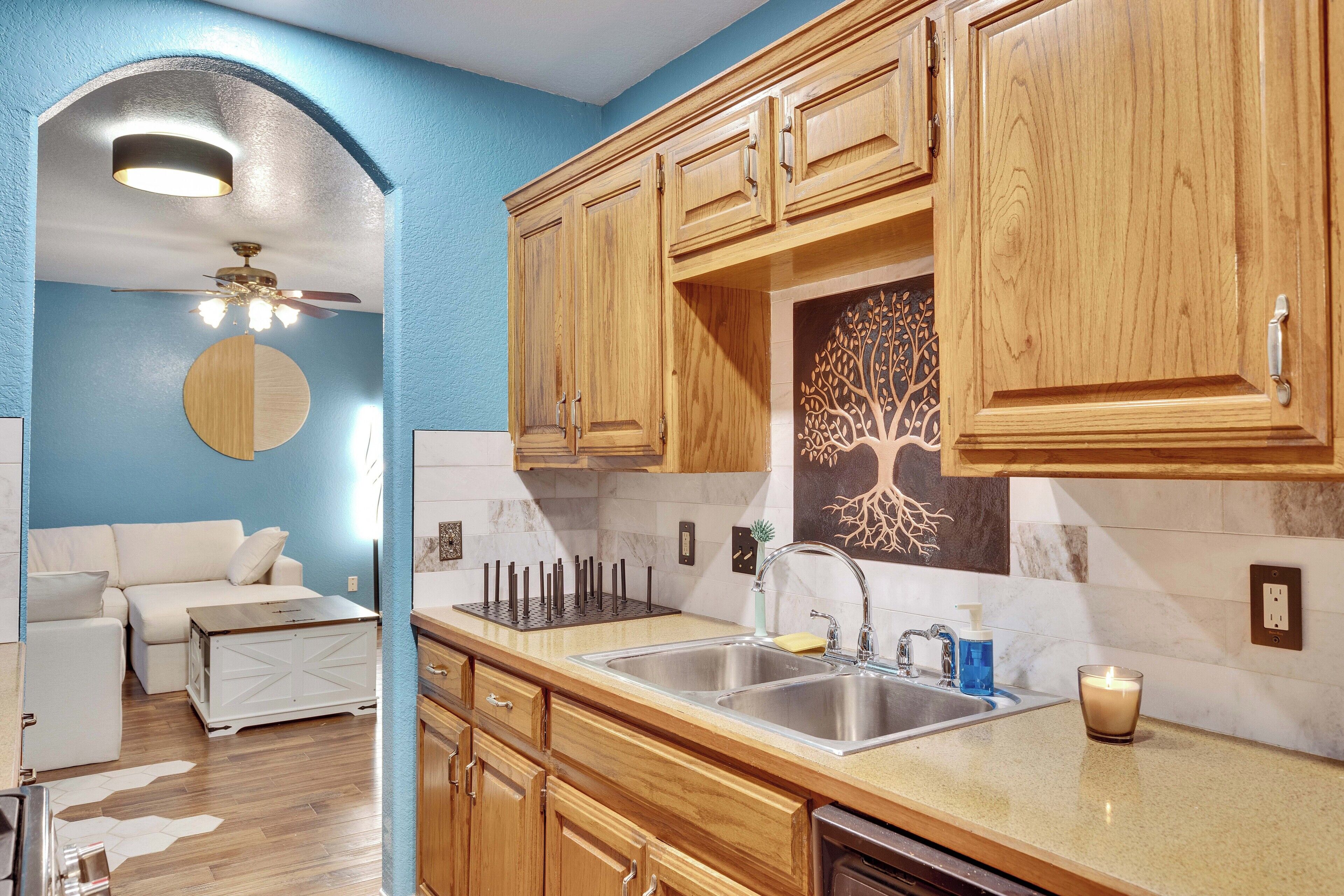 A kitchen with wooden cabinets, a double sink, and a ceiling fan.