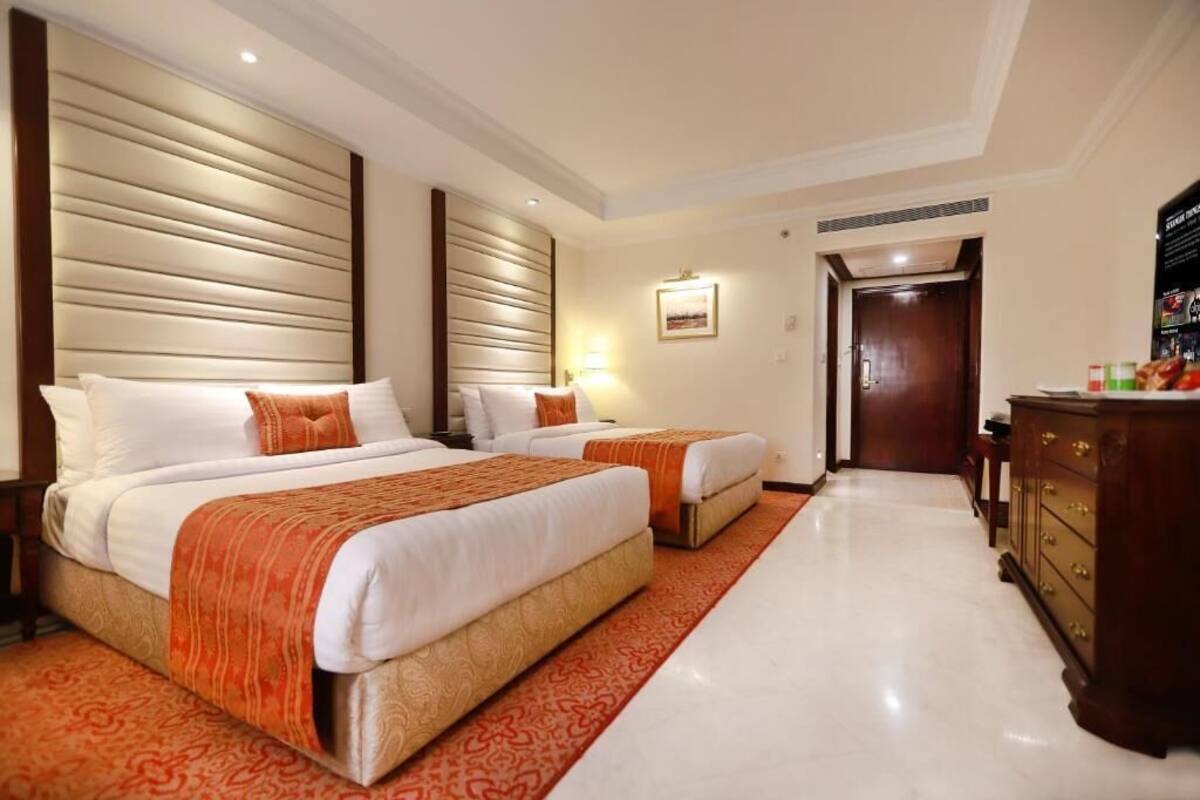 Een hotelkamer met twee bedden, een houten dressoir en een vloerbedekking.