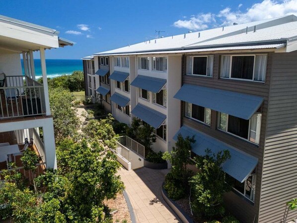 A multi-story hotel with balconies overlooking a beach.