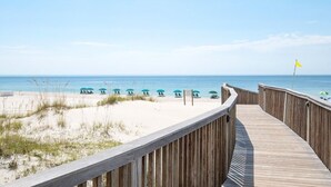 Une promenade en bois menant aux parasols de plage.