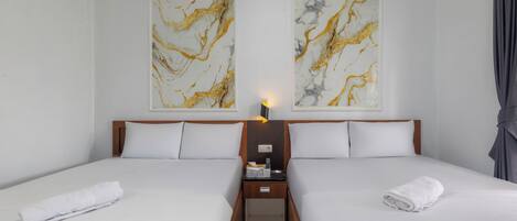 A hotel room with two beds, a nightstand, and artwork on the walls.