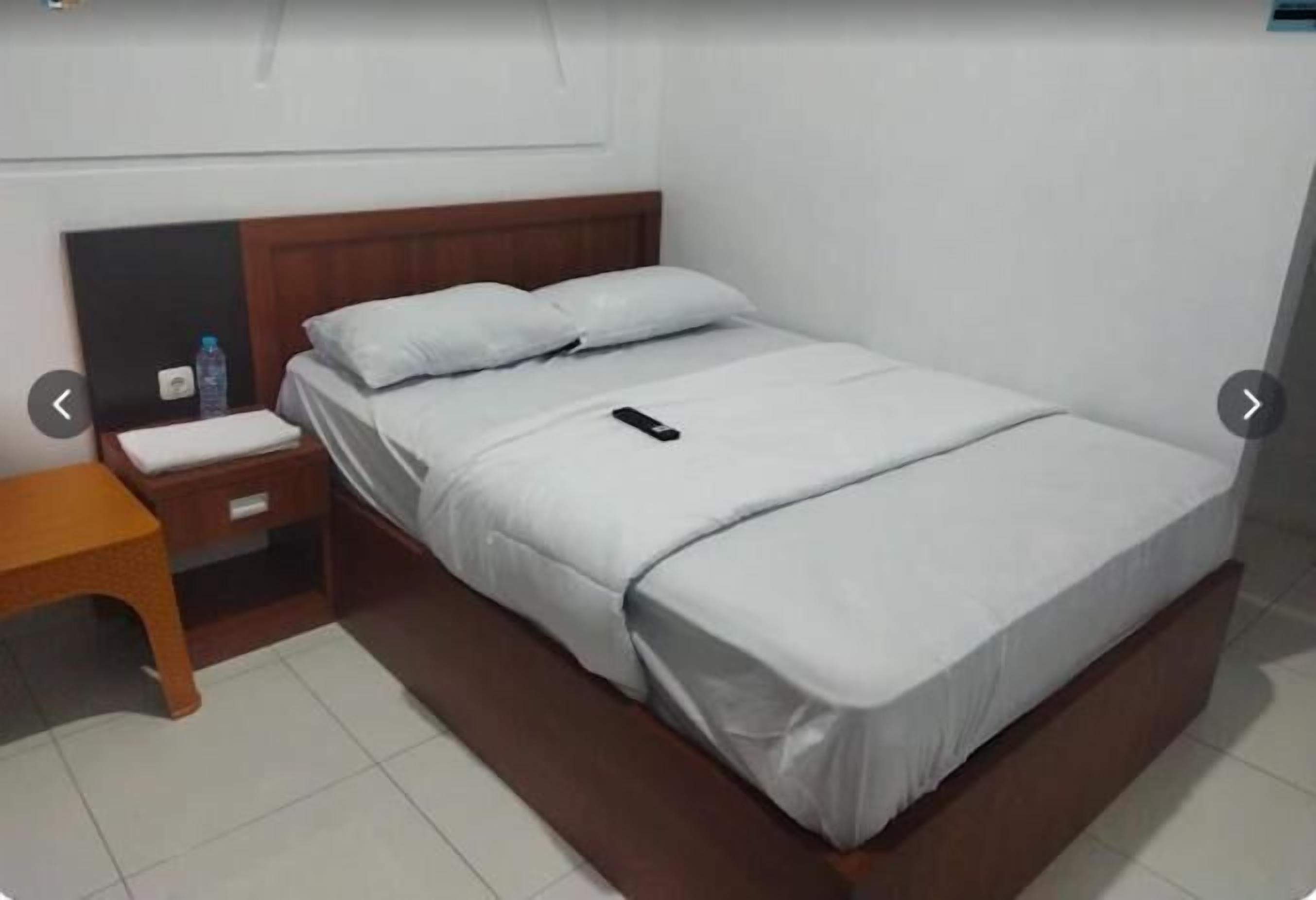 A single bed with a wooden headboard, a bedside table, and a nightstand.