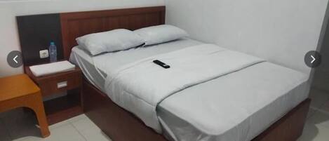 A single bed with a wooden headboard, a bedside table, and a nightstand.