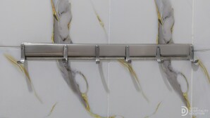 Ein Badezimmer mit weißer Marmorwand und einem Metallhandtuchhalter.