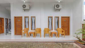 Un espace d’accueil d’hôtel comprenant un coin salon avec des portes en bois, des unités de climatisation et des fauteuils en osier.