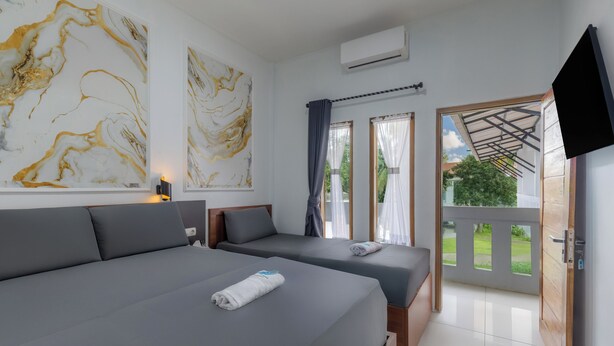 Une chambre moderne avec deux lits, de grandes peintures abstraites, une télévision et un balcon offrant une vue sur la verdure.