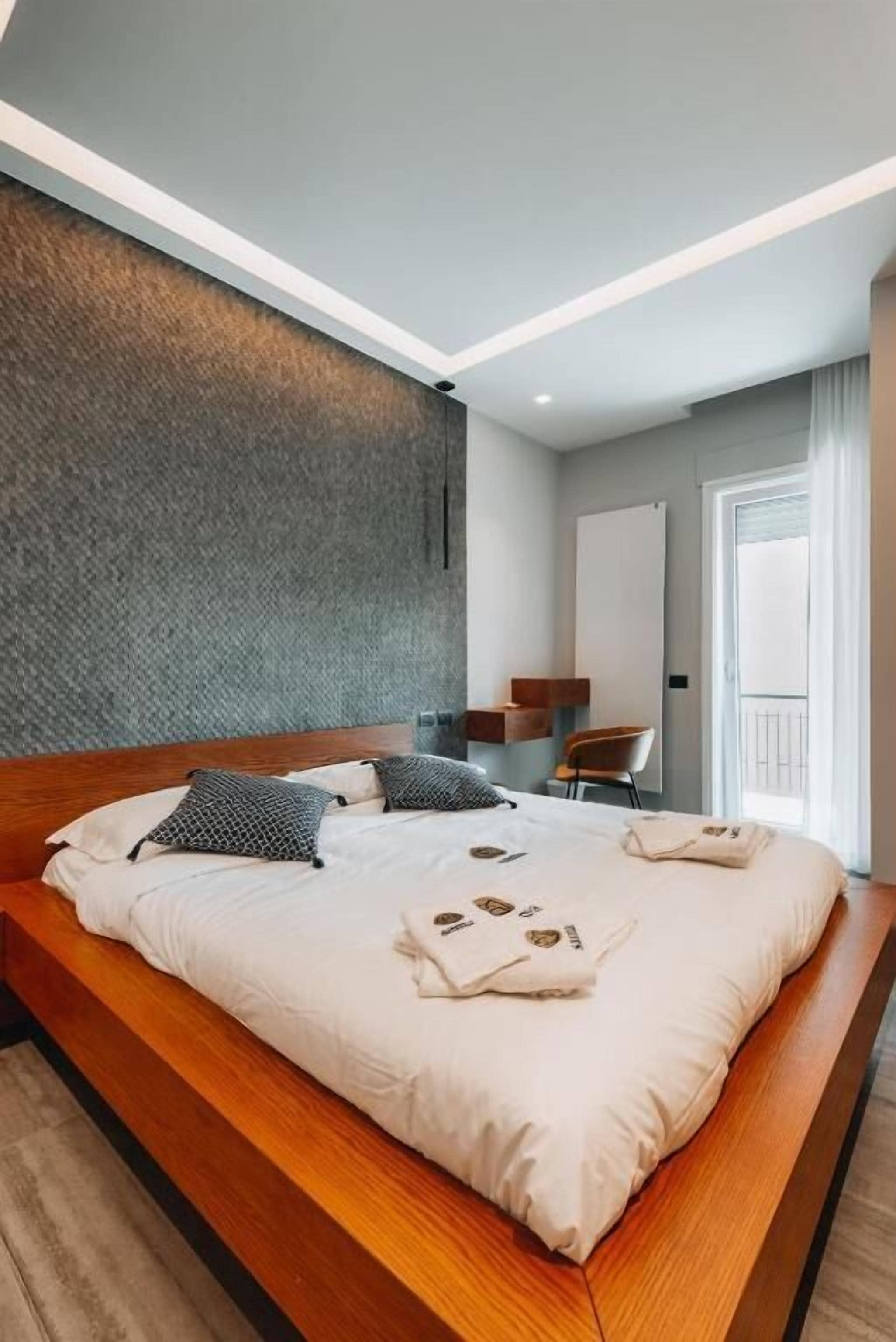 Quarto de hotel moderno com uma cama grande, uma escrivaninha e vista para o exterior.