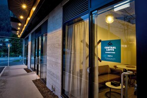 Ein modernes Gebäude mit Glasüren, einem Schild für Central Lofts Queenstown Unit 4 und einem Sitzbereich mit Tisch und Stühlen.
