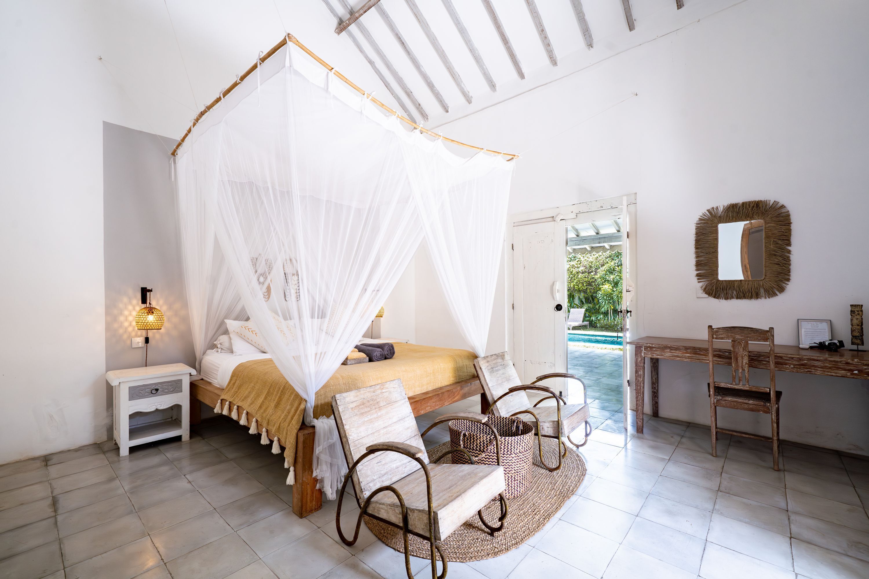 A bedroom with a bed, bedside table, chair, and a desk with a chair.