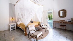 A bedroom with a bed, bedside table, chair, and a desk with a chair. - Villa Zen Bingin (Pecatu)