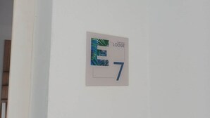 Paredão branco com uma placa indicando o quarto número 7, identificada como 'TRACADENO LODGE'.