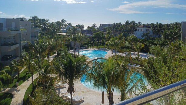 Piscina de resort rodeada por palmeiras e edifícios modernos.