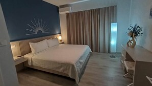 Quarto de hotel moderno com uma cama grande, mesas de cabeceira, uma escrivaninha e vista para o exterior através de uma janela com cortinas.