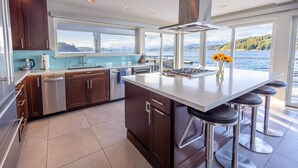 A modern kitchen with a large island, stainless steel appliances, and a view of a lake. - Hood Canal Resort in Union, WA (Union)