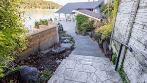 A stone staircase leading to a modern house with a view of a lake. - Walls of Glass (Union)