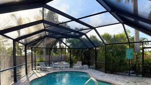 A covered swimming pool with a patio area, surrounded by a fence and trees. - Englewood Escape – Pet Friendly + Heated Pool (Englewood)