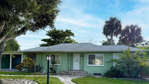 A single-story house with a green exterior, a stone pathway leading to the front door, and a small front yard with a tree and shrubbery. - Englewood Escape – Pet Friendly + Heated Pool (Englewood)
