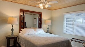 A bedroom with a bed, two bedside tables with lamps, a ceiling fan, a window with blinds, and a wooden headboard. - Englewood Escape – Pet Friendly + Heated Pool (Englewood)