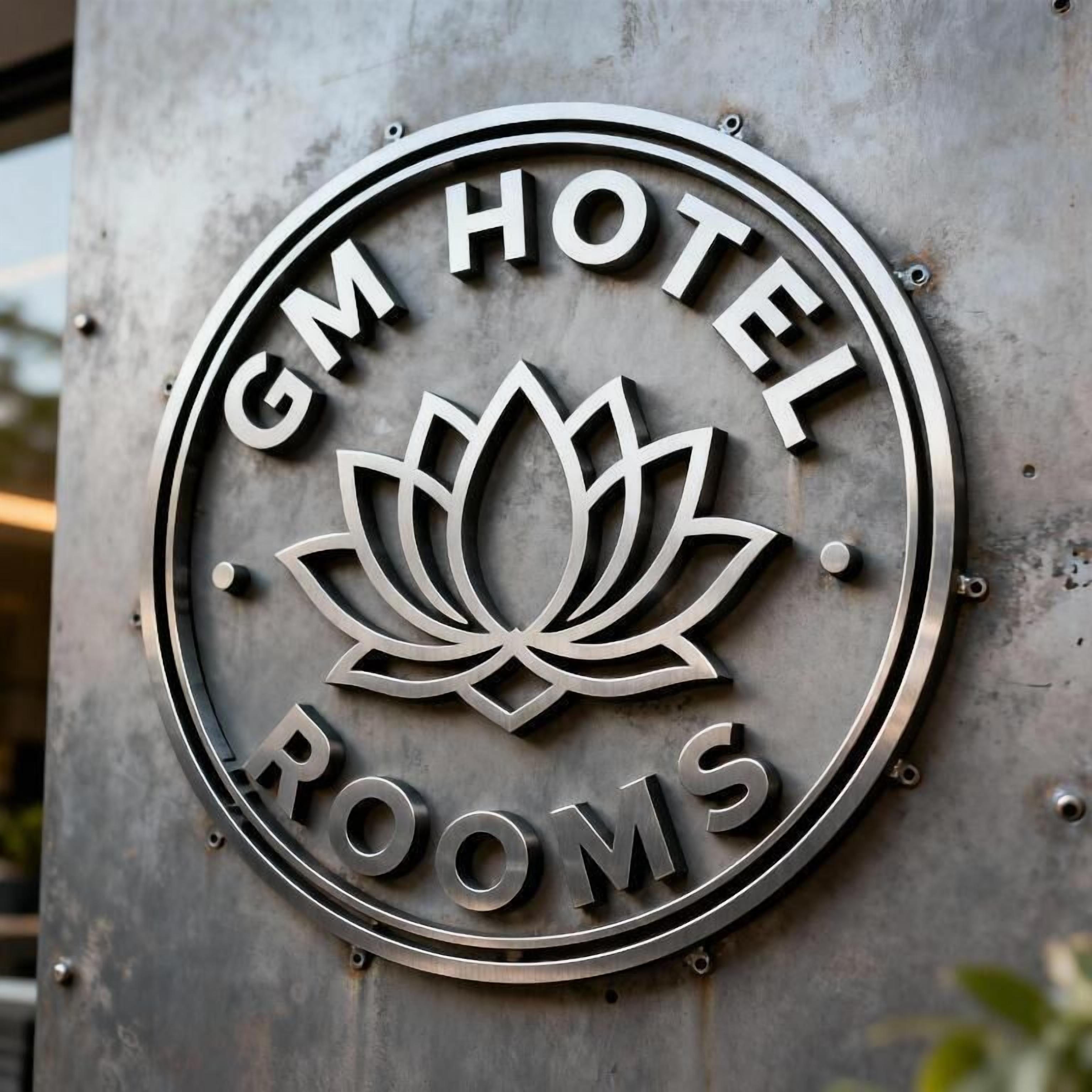 Un logo circulaire avec le texte « GM HOTEL ROOMS » et un motif représentant une fleur de lotus.