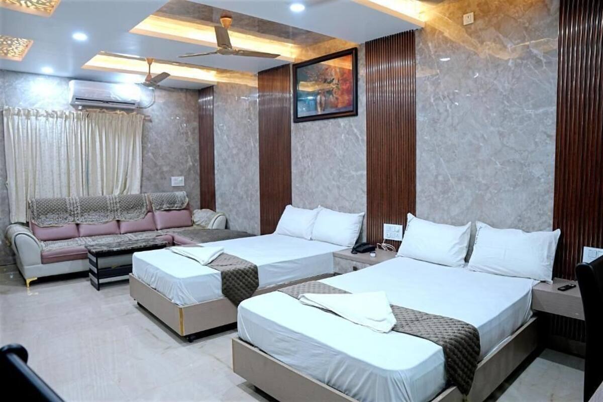 Une chambre d’hôtel avec deux lits, un canapé, un bureau et un appareil de climatisation.
