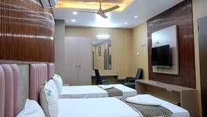 Quarto de hotel com duas camas, televisão, escrivaninha e ventoinha no teto.