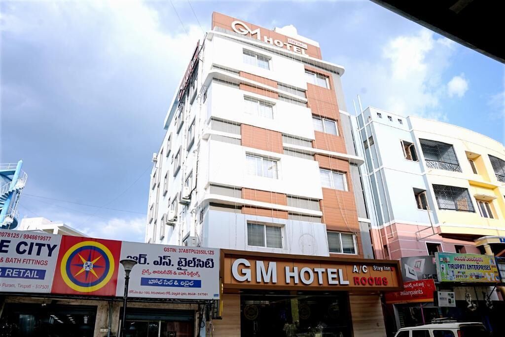 A multi-story hotel with signage for 'GM HOTEL' and 'A/C Stay Inn Rooms.'