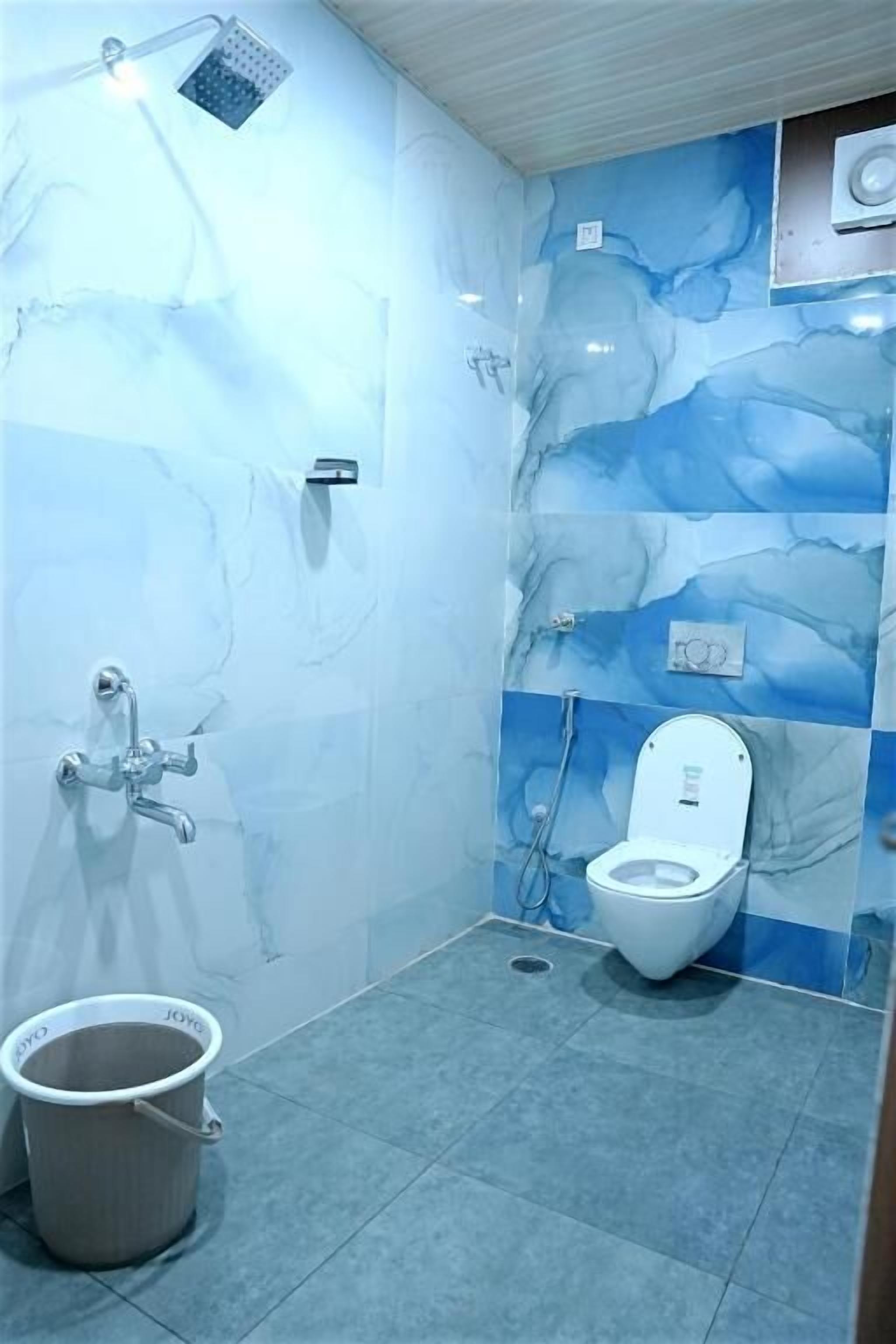 A bathroom with a toilet, shower, and a bucket.
