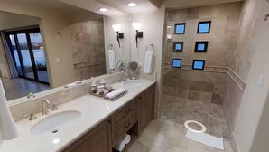 Een moderne badkamer met twee wasbakken, een grote spiegel en een douchegedeelte.