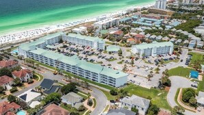 An aerial view of a coastal hotel with multiple buildings, parking areas, and a beach in the background. - 🏖️ 5⭐️ Maravilla 4108!☀️Beautiful Remodel! 1 Bd 1.5 Bath w Bunks-Beach Svc 2Pools! (Miramar Beach)