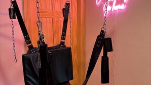 A room with a hammock chair suspended from the ceiling, a neon sign on the wall, and a wooden door. - Kinky ADULTS ONLY studio in vibrant Nashville (Nashville)