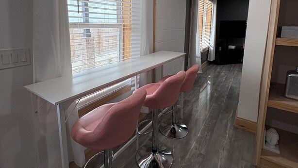 A modern kitchen with a white countertop, two pink bar stools, and a window with blinds. - Kinky ADULTS ONLY studio in vibrant Nashville (Nashville)