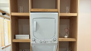A white washing machine in a wooden cabinet with shelves, a small statue, and a basket. - Kinky ADULTS ONLY studio in vibrant Nashville (Nashville)
