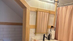 A bathroom with a white sink, black cabinet, wooden ceiling beams, and a mirror with a light fixture above it. - Kinky ADULTS ONLY studio in vibrant Nashville (Nashville)