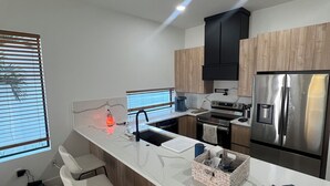A modern kitchen with a central island, stainless steel appliances, and bar stools. - 1 mile to Downtown St Petersburg new construction luxury 2,155 sqft home (St. Petersburg)