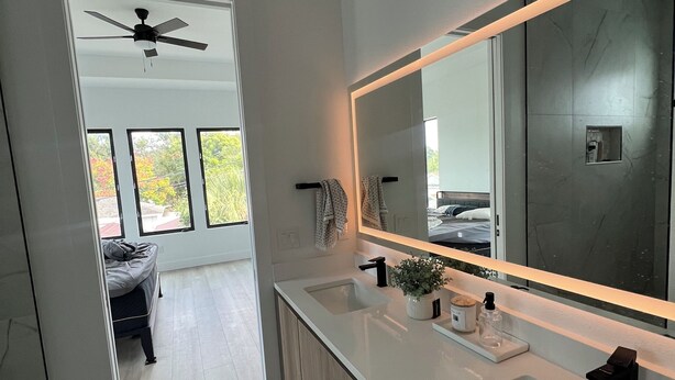 A modern bathroom with a large mirror, two sinks, and a ceiling fan. - 1 mile to Downtown St Petersburg new construction luxury 2,155 sqft home (St. Petersburg)
