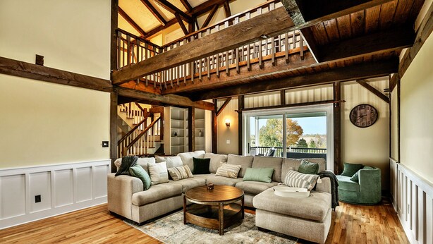 Ein geräumiges Wohnzimmer mit einem großen Ecksofa, einem Couchtisch und einer Treppe mit Holzbalken.