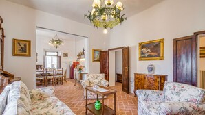 A spacious living room with floral upholstery sofas, a wooden coffee table, and a chandelier. - Chianti Classico Home Panoramic View 4, Castellina in Chianti, Italy (Castellina in Chianti)