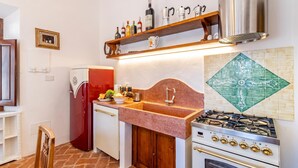 A kitchen with a red refrigerator, a sink with a wooden countertop, and a gas stove. - Chianti Classico Home Panoramic View 6, Castellina in Chianti, Italy (Castellina in Chianti)