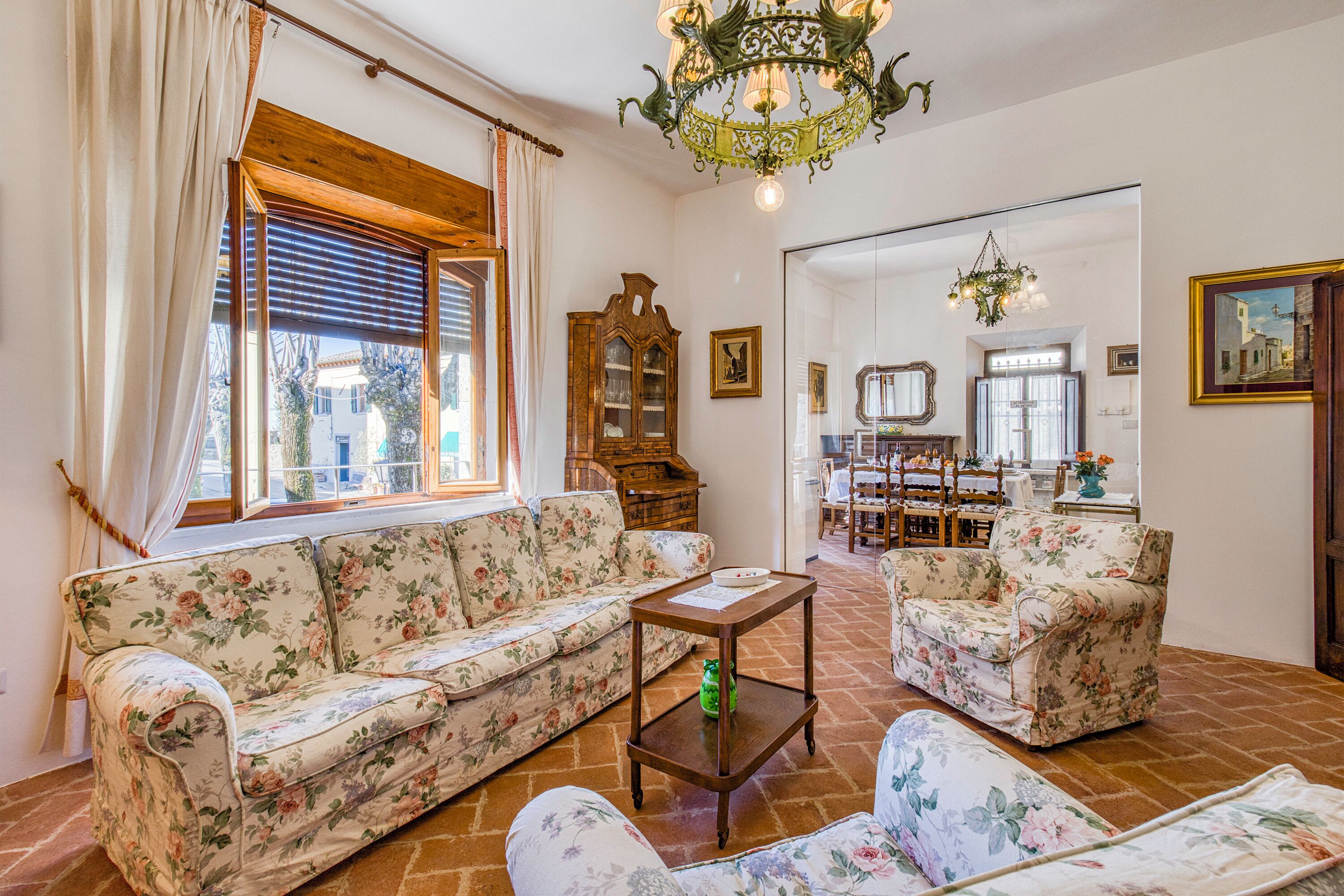 A living room with a floral sofa, a wooden coffee table, and a chandelier.