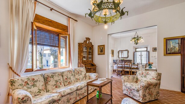 A living room with a floral sofa, a wooden coffee table, and a chandelier. - Chianti Classico Home Panoramic View 6, Castellina in Chianti, Italy (Castellina in Chianti)