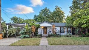 A single-story house with a front porch, a covered garage, and a fenced yard.